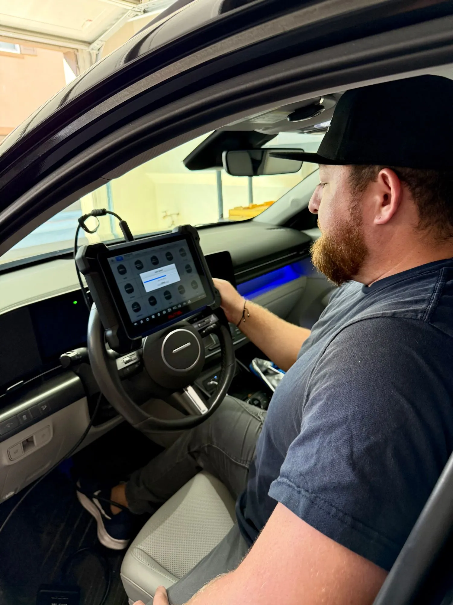 Garrett in the driver's seat holding the key-programming tablet, cabled to the car.